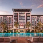 Wide architectural view of the exterior of Belgravia Gardens by Ellington Properties, showing the central courtyard, swimming pool, and modern apartment buildings under a clear sky.